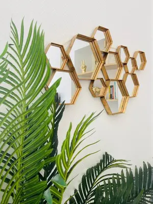 a gold mirror hanging on a wall next to a plant at Le somptueux Le Gallia in Cannes