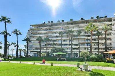 a large white building with palm trees in front of it at Luxurious apartment with terrace 6P - 3BR - Grand in Cannes