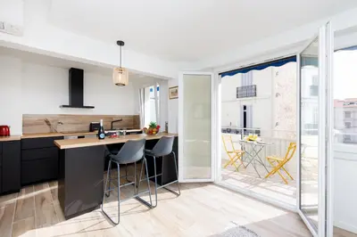 a kitchen with black cabinets and a counter with stools at Palladium 148 YourHostHelper in Cannes