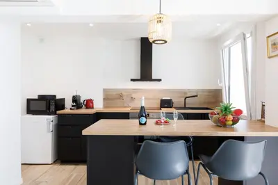 a kitchen with a large wooden island with chairs at Palladium 148 YourHostHelper in Cannes