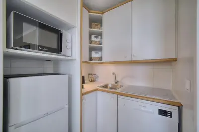 a small kitchen with a microwave and a refrigerator at IMMOGROOM - Renovated - Sea view - Pool - Patio - Wifi - AC - Parking in Cannes