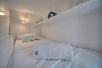 a small bedroom with a bed with white sheets at IMMOGROOM - Renovated - Sea view - Pool - Patio - Wifi - AC - Parking in Cannes