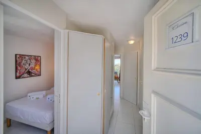 a white room with a bed and a hallway at IMMOGROOM - Renovated - Sea view - Pool - Patio - Wifi - AC - Parking in Cannes