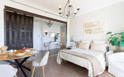 a bedroom with a bed and a table and a dining room at Bel Appartement 5* Vue Mer Et Suquet - Centre Cannes in Cannes