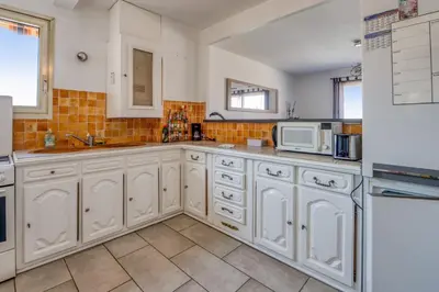 a large kitchen with white cabinets and appliances at Appartement Berthelotine - Welkeys in Cannes