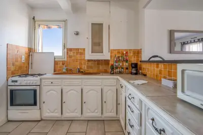 a kitchen with white cabinets and a sink and a microwave at Appartement Berthelotine - Welkeys in Cannes