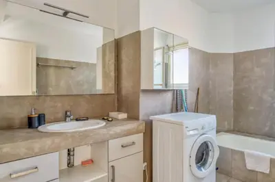 a bathroom with a sink and a washing machine at Appartement Berthelotine - Welkeys in Cannes