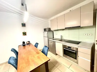 a kitchen with a wooden table and a wooden table and chairs at Jolie 3 pièces avec terrasse au vieux port, à 2 pas des plages et du palais. in Cannes
