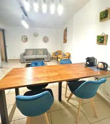 a dining room with a wooden table and blue chairs at Jolie 3 pièces avec terrasse au vieux port, à 2 pas des plages et du palais. in Cannes