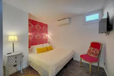 a small bedroom with a bed and a red chair at Le Louvre Top Floor in Cannes