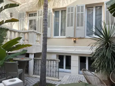 a bedroom with a bed and a kitchen with a table at Villa les Fougeres Studio jardin in Cannes