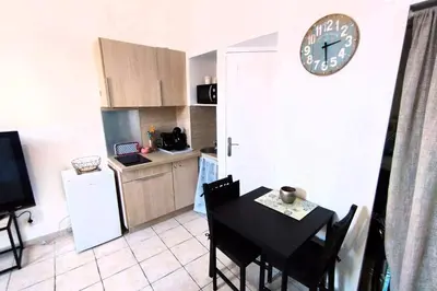 a kitchen with a table and a clock on the wall at Charming Studio ideal for Congresses and Holidays LIVE IN GAZAGNAIRE in Cannes