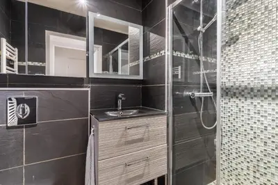a black bathroom with a sink and a shower at La Villa Gauguin in Le Cannet