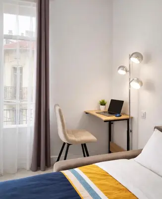 a bedroom with a bed and a desk with a laptop at Cannes centre apartment with a balcony in Cannes