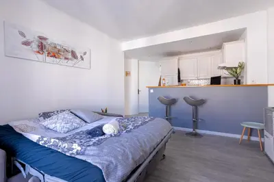 a bedroom with a blue bed and a kitchen at Cannes centre apartment with a balcony in Cannes