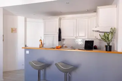 a kitchen with white cabinets and two stools at Cannes centre apartment with a balcony in Cannes