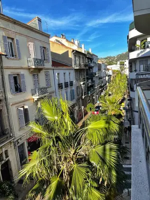 a city street with palm trees and buildings at Cannes centre apartment with a balcony in Cannes
