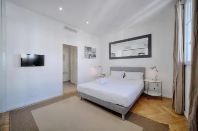 a white bedroom with a bed and a mirror at REF 909 - Cannes Back Croisette - Apartment for rent in Cannes
