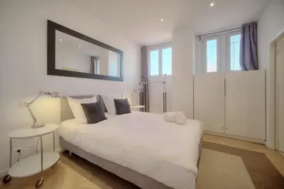 a bedroom with a white bed and a mirror at REF 909 - Cannes Back Croisette - Apartment for rent in Cannes