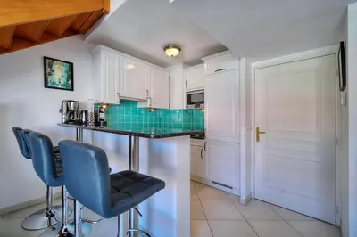 a kitchen with white cabinets and blue bar stools at REF 1766 - Cannes Center - Apartment for rent in Cannes