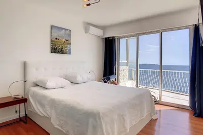 a bedroom with a white bed and a large window at REF 1769 - Cannes - Sea view penthouse for rent in Cannes