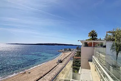 a view of a beach with a building and the ocean at REF 1769 - Cannes - Sea view penthouse for rent in Cannes