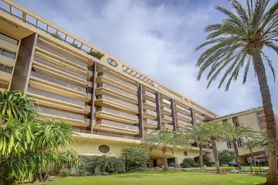 a large building with palm trees in front of it at REF 1389 - Cannes Center - Apartment for rent in Cannes