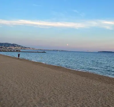 a person standing on a beach near the water at Évasion aux Portes de Cannes 100m2 Lumineux 2 Chambres Terrasse et Commerces in Le Cannet