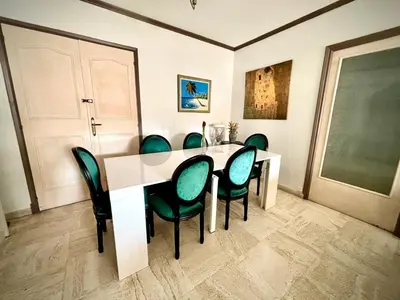 a dining room with a white table and green chairs at Évasion aux Portes de Cannes 100m2 Lumineux 2 Chambres Terrasse et Commerces in Le Cannet