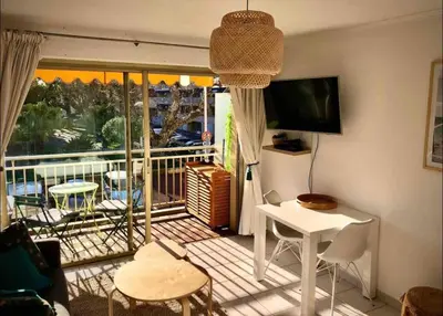a living room with a balcony with a table and a television at Le Bleuette - Festivals 10min - face plages ! in Cannes