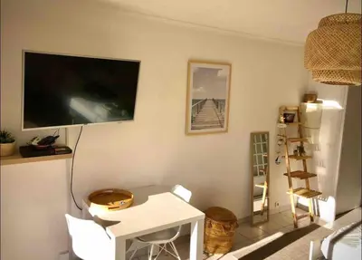 a living room with a table and a tv on the wall at Le Bleuette - Festivals 10min - face plages ! in Cannes