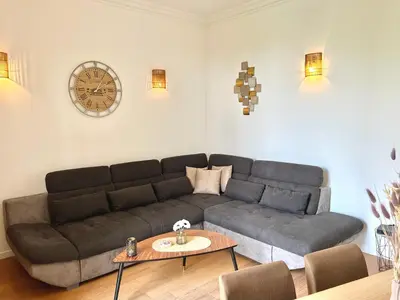 a living room with a couch and a clock on the wall at Top emplacement centre Cannes in Cannes