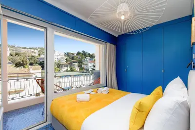 a blue bedroom with a bed and a large window at Les Légendes YourHostHelper in Cannes