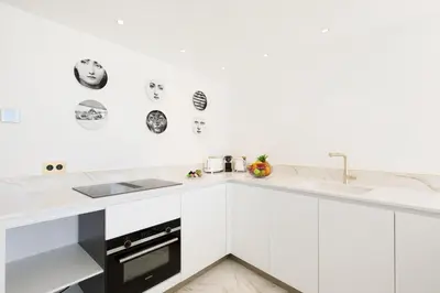 a white kitchen with white cabinets and a sink at Les Légendes YourHostHelper in Cannes