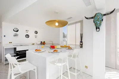 a white kitchen with a table and stools at Les Légendes YourHostHelper in Cannes