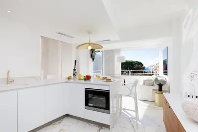 a white kitchen with a fireplace and a couch at Les Légendes YourHostHelper in Cannes