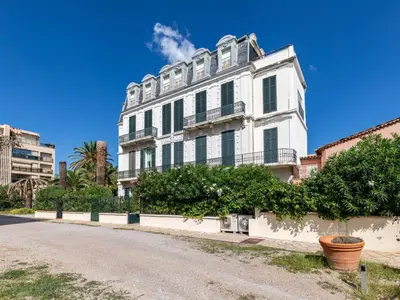 a white building on the side of a road at Apartment Les Araucarias by Interhome in Cannes