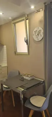 a glass table with two chairs and a clock on the wall at STUDIO CANNES STELLAMARE in Cannes