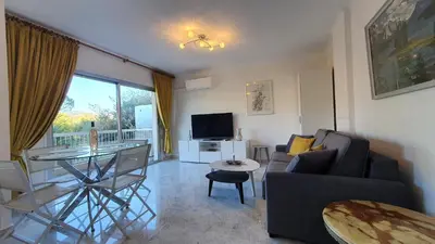a living room with a couch and a table and a television at Centre Cannes gd 2p terrasse parking 10mn palais plage in Cannes