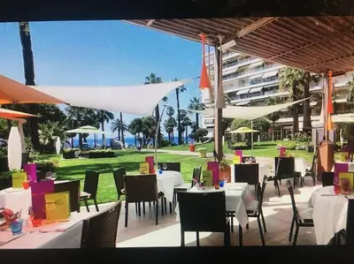 a restaurant with white tables and chairs and a building at Eider croisette in Cannes