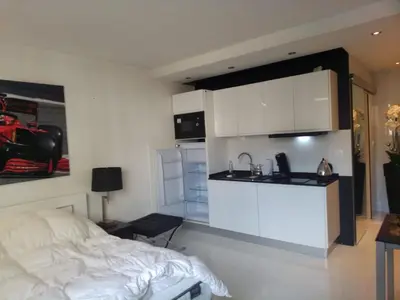 a bedroom with a bed and a kitchen with white cabinets at Eider croisette in Cannes