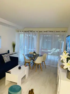 a living room with a couch and a table and chairs at 3 pièces terrasse, jardin in Cannes