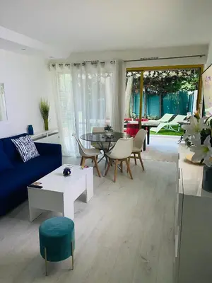 a living room with a blue couch and a table and chairs at 3 pièces terrasse, jardin in Cannes