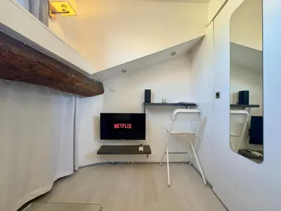 a room with a tv and a chair in it at Mini Studio - Le Chabaud - Cannes centre in Cannes