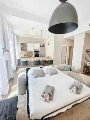 a bedroom with a large white bed and a living room at Cannes Vidal Rue Antibes SNCF station 2 mn 1 BR new 2024 quiet building hyper center by Olam Properties in Cannes