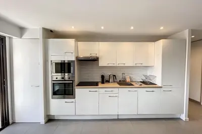 a white kitchen with white cabinets and appliances at Stunning 1 BR 3 pers Résidence Cannes Suquet Vieux Port Croisette 1 mn by Olam Properties in Cannes