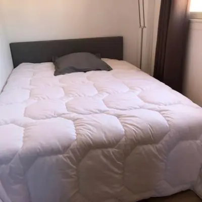 a white bed with a pillow on top of it at 2 pièces 2 terrasses 100 m Croisette très clair. in Cannes