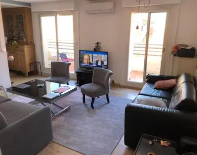 a living room with a couch and a tv at 2 pièces 2 terrasses 100 m Croisette très clair. in Cannes