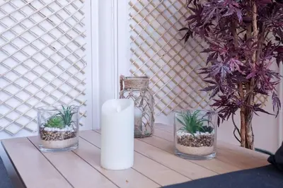 a table with a candle and three plants in glass jars at Luxury Apt With Large Terrace On Famous Rue D'antibes! - Pasteur Apt by Halldis in Cannes
