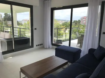 a living room with a couch and a table and a balcony at Appartement montfleury, 2 terrasses, 2 chambres , 2 sdb , pkg privé piscine, 15 min walk to Croisette beach and Palais des festivals in Cannes